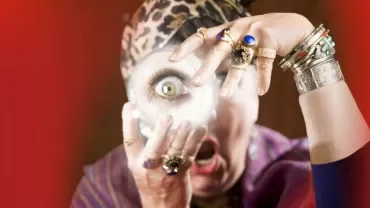Person wearing rings analyzing a crystal ball with excitement.