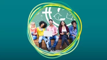 Group of people sitting with devices, smiling in front of a green wall with symbols.