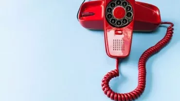 Red rotary phone on a blue background.