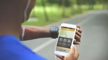 Personne vérifiant l'heure sur un smartphone pendant l'exercice en extérieur.