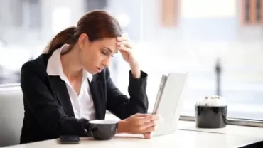 Persoon in een café kijkt naar een tablet met koffie op tafel.