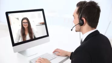 Personne utilisant un ordinateur pour un appel vidéo au bureau.