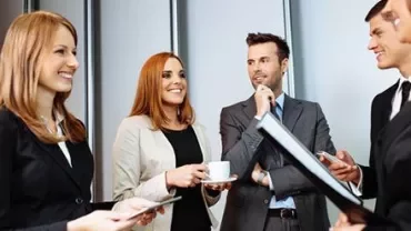 Groupe de personnes en tenue professionnelle discutant amicalement.