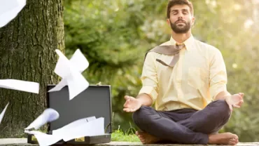 Person meditating near a tree with papers flying from a briefcase.