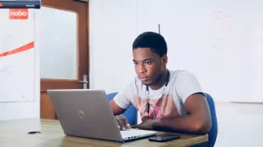 Person working on a laptop at a desk in an office.