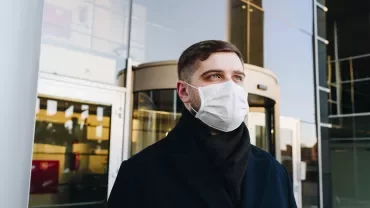 Personne portant un masque à l'extérieur d'un bâtiment