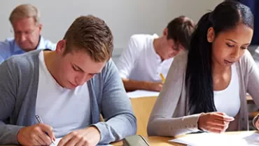 Studenten die zich concentreren op een schriftelijk examen in een klaslokaal.
