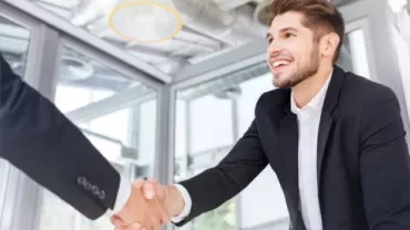 Person smiling during a handshake in an office setting.