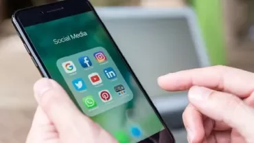 Main tenant un smartphone affichant des applications de médias sociaux.
