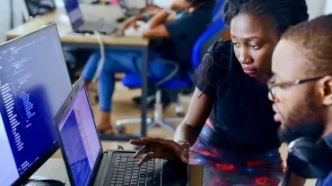 Twee mensen werken samen aan een computer op kantoor.