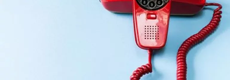 Red rotary phone on a blue background.