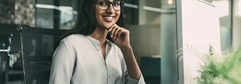 Person smiling at a desk in a modern office.