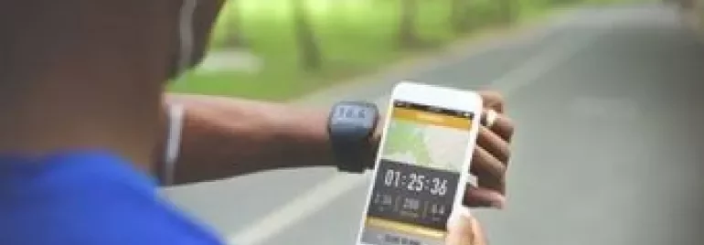Personne vérifiant l'heure sur un smartphone pendant l'exercice en extérieur.