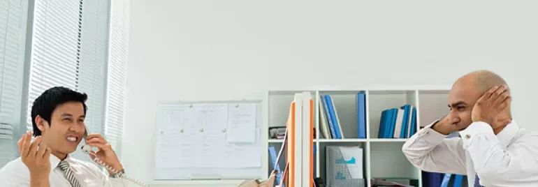 Two people working in an office with one talking on the phone.