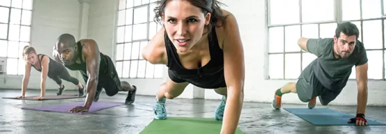 Groep doet plankoefening in een lichte fitnessruimte.
