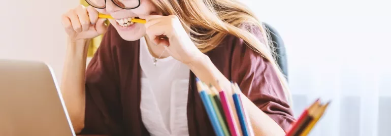 Personne mordant un crayon en regardant un ordinateur portable.