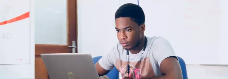 Persoon werkt op een laptop aan een bureau op kantoor.