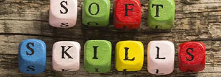 Des cubes en bois colorés épellent 'soft skills' sur une surface rustique.