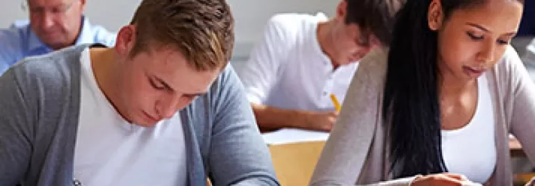 Étudiants concentrés sur un examen écrit en classe.