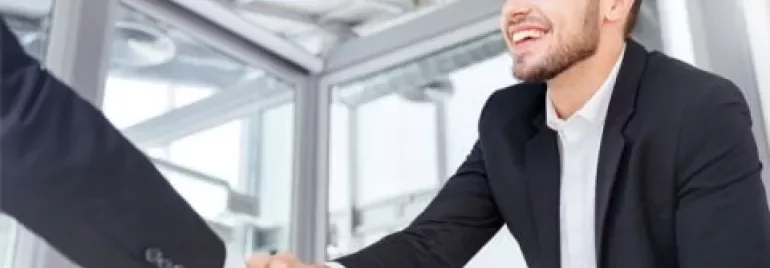Personne souriant pendant une poignée de main dans un bureau.