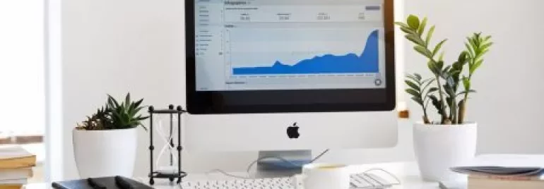 Ordinateur sur un bureau avec un graphique à l'écran, entouré de plantes et de livres.