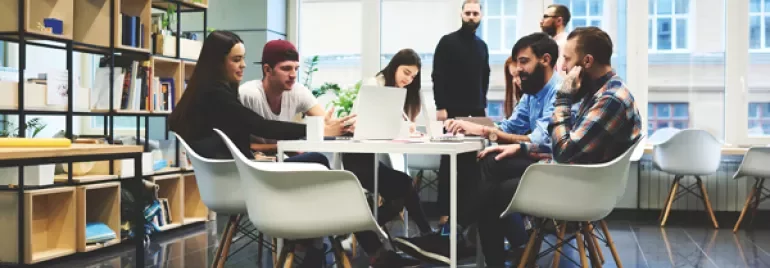 Team collaborating around a table in a modern office space.