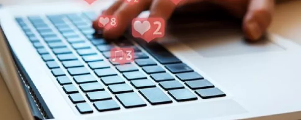 Hand typing on laptop keyboard with notification icons overlayed.